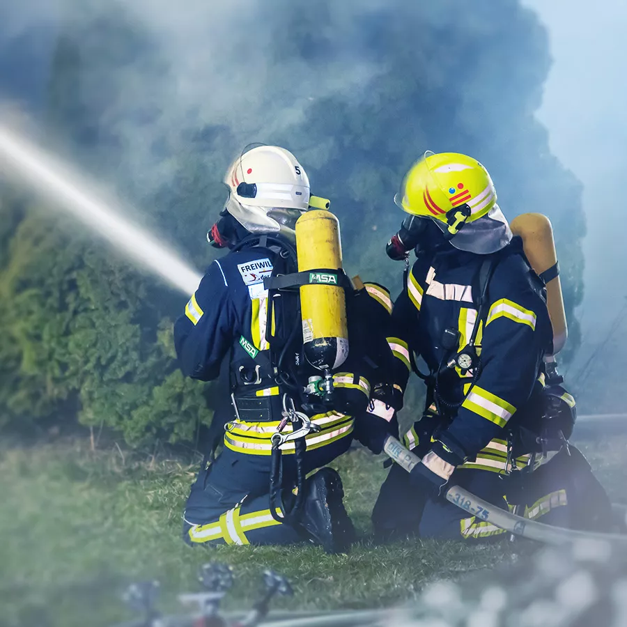 Feuerwehrleute beim Löscheinsatz mit Strahlrohr und Wassernebel